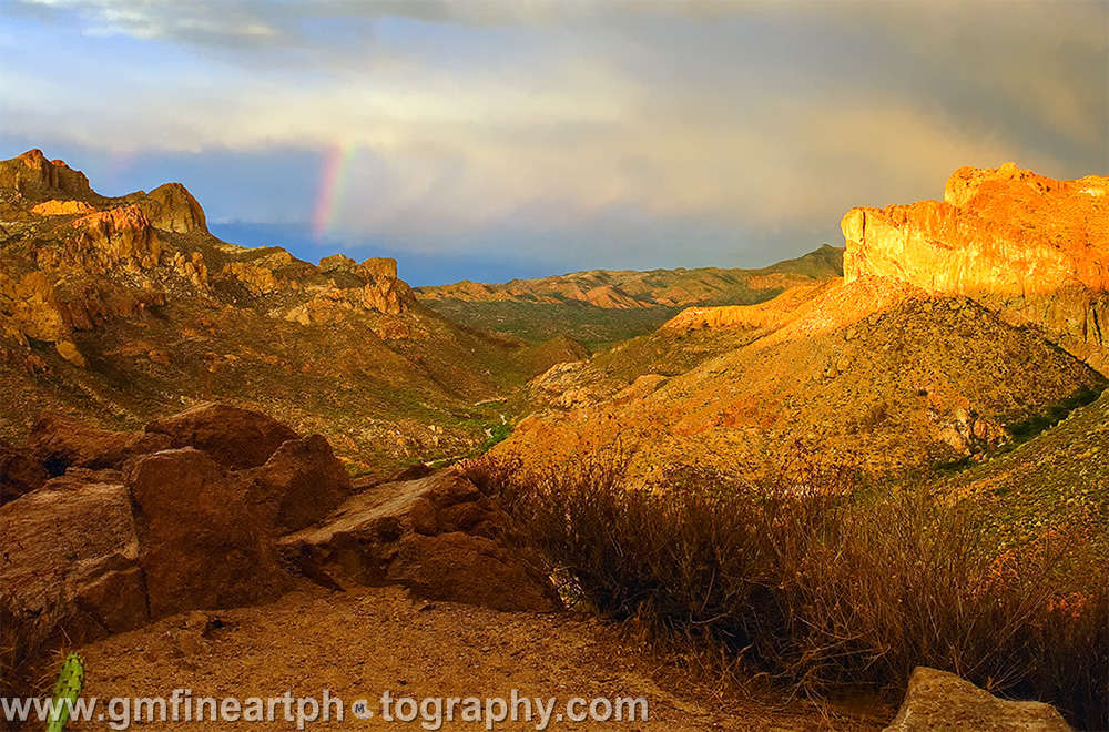 golden sunset with a rainbow between two mountains in the southwest desert