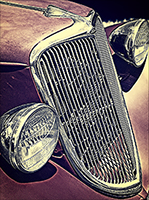 A tilted front end of a 1934 Ford with red oxide primer