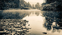rocks in front of a very calm river flowing through mountains